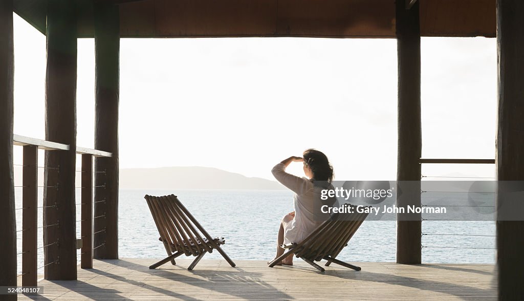 Woman sitting on veranda looking out to sea