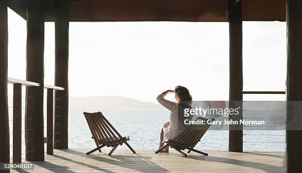 woman sitting on veranda looking out to sea - whitsunday island stock pictures, royalty-free photos & images