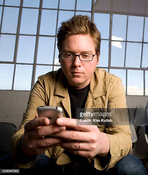 Isaac "Biz" Stone, co-founder and Creative Director of Twitter, Inc. Tweets a message on his iPhone in their San Francisco, California headquarters.