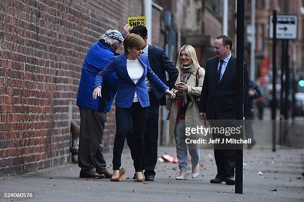 Leader and First Minister Nicola Sturgeon, has the heel of her shoe caught by local candidate Humza Yousaf as they arrive at BAE Systems in Govan...
