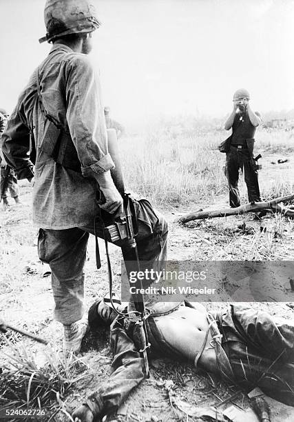 American GI photographs his First Cavalry Division buddy with the corpse of a North Vietnamese Army soldier he has just shot in fighting in South...
