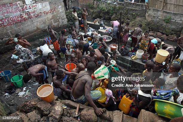 People get water, clean clothes and wash themselves by a water pipe in Susan's Bay slum in Freetown, Sierra Leone, November 9, 2008.