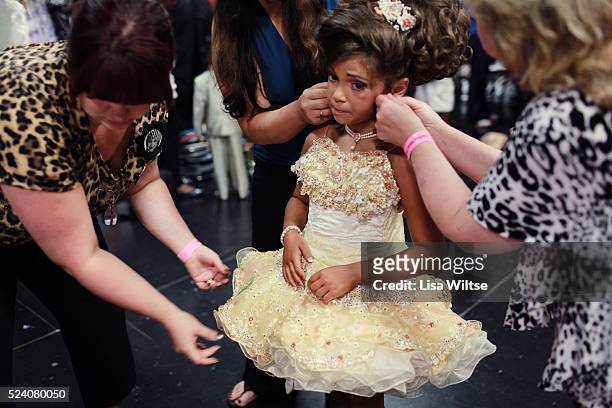 Age 8, gets help from her Grandmother to put on the final touches of hair spray and adjusts her costume before she goes on stage during the Darling...