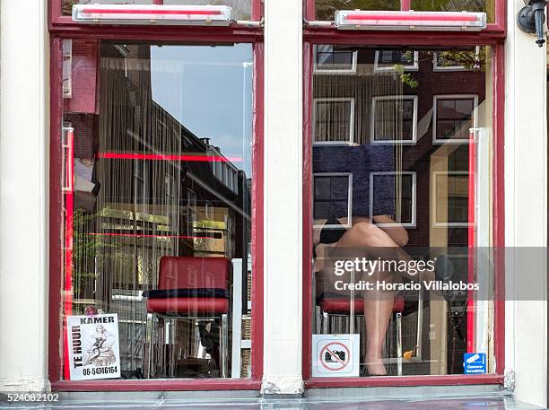 Prostitute covers her face with a cushion to avoid being photographed, at her prostitution window-booth, which at the side of another for rent, in...