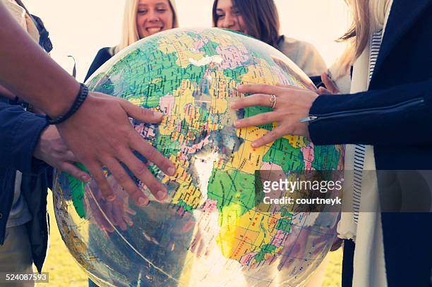 group of young people holding a world globe - student visa stockfoto's en -beelden