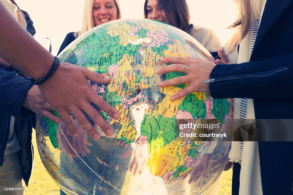 Group of young people holding a world globe