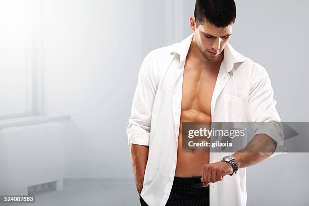 handsome muscular man with a wristwatch. - fully unbuttoned stockfoto's en -beelden