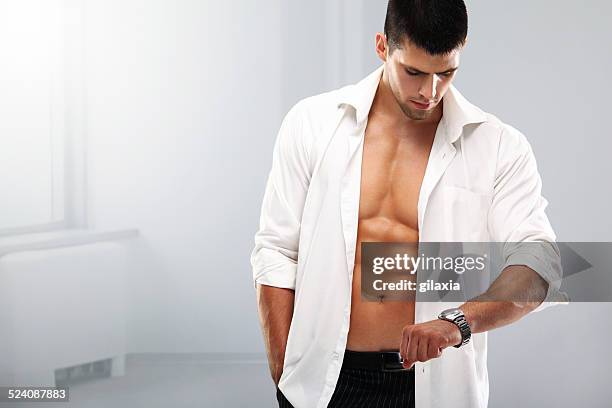 handsome muscular man with a wristwatch. - unbuttoned shirt 個照片及圖片檔