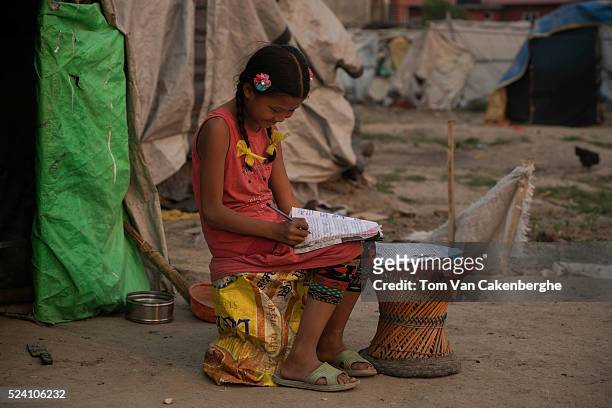 Shanti Tamang does her homework after school outside her shelter at Chuchepati displacement camp, a sprawling squalid displaced shelter for...