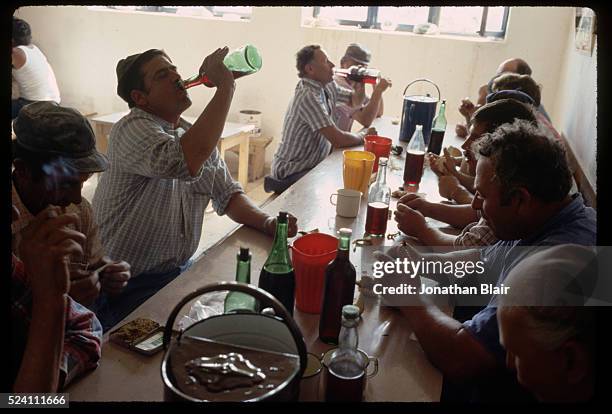 Men drink from bottles of wine on their morning break, known as a miranda, at the Brac Stone Quarry in Pucisca, Croatia, Yugoslavia.