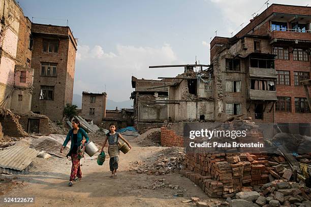 Women walk through a destroyed neighborhood to get water from a well on April 25, 2016 in Bhaktapur, Nepal. One year after the devastating...