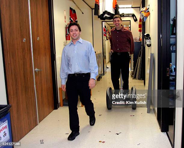 Sergey Brin , Co-Founder and President, Technology walks while Larry Page, Co-Founder and President, Products, rides a Segway Human Transporter...