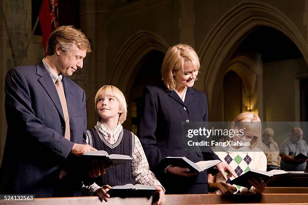 family standing and praying in church - protestantism stock pictures, royalty-free photos & images