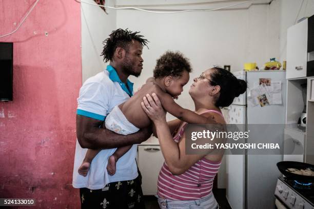 Popole Misenga a refugee judoka from the Democratic Republic of Congo, passes his one-year-old son Heliasin to his partner Fabiana at their home in...