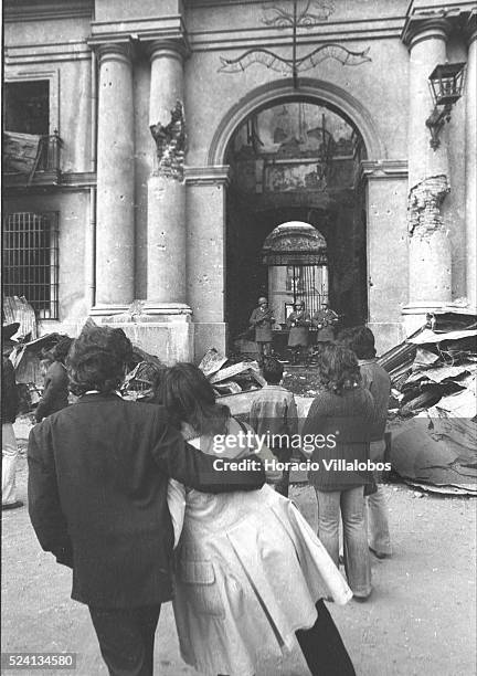 Couple and some kids watch the gutted main entrance of La Moneda, during the aftermath of the coup d'etat led by Commander of the Army General...