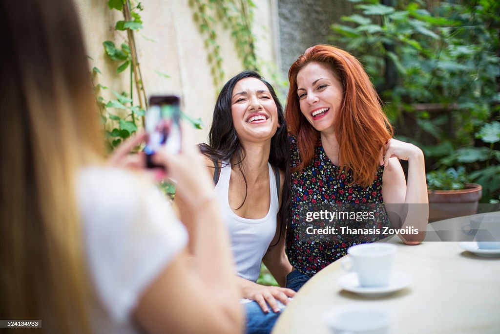 Young woman taking picture of her friends in cafe