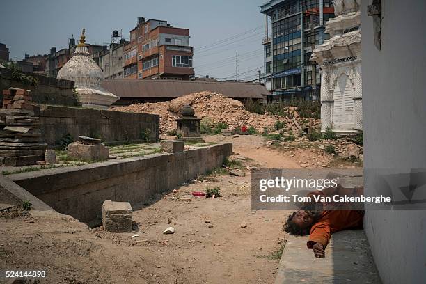 Hindu holy man, or Sadhu, sleeps on the steps of a small temple next to the Kalmochan Mahadev temple that was reduced to a hill of sand and bricks on...