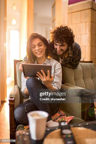 smiling couple at home using touchpad. - couple with ipad in home stock pictures, royalty-free photos & images