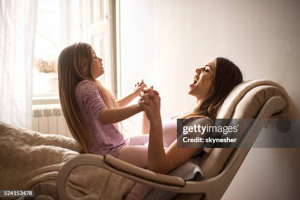 glückliche mutter und tochter sitzen im schaukelstuhl und singen. - schaukelstuhl stock-fotos und bilder