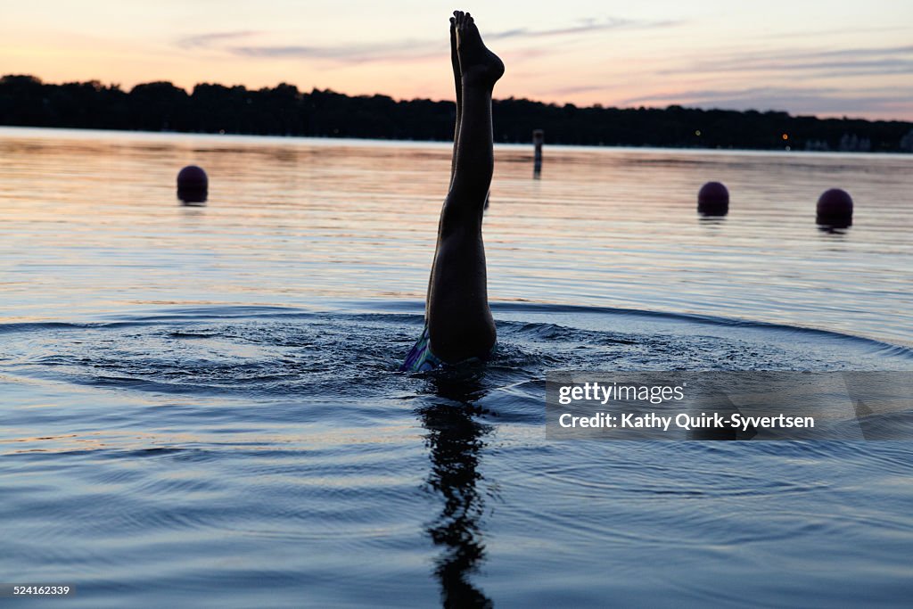 Girl diving in lake at sunset