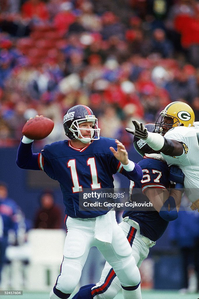 Quarterback Phil Simms of the New York Giants passes under pressure ...