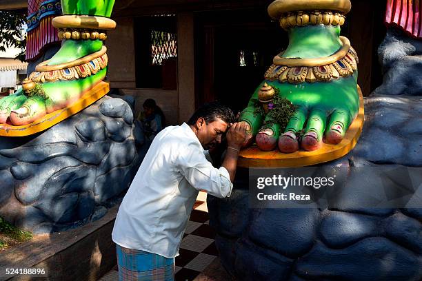 January 2013, Channarayapattana, India. A man prays in the feet of the statue of the Indian God Hanuman, at the head of monkey, in the entrance of a...