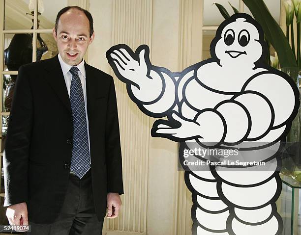 Chairman of tyre maker company Michelin Edouard Michelin poses next to a cardboard cutout of the Michelin Man during the presentation of the results...