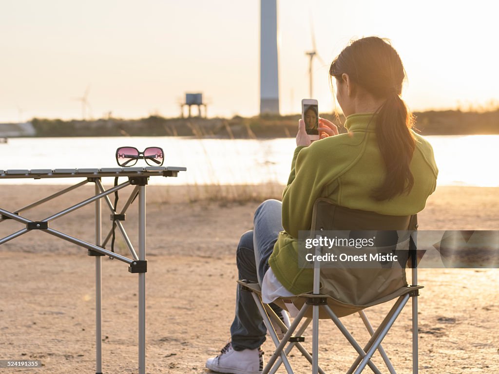 Young woman using smart phone in campsite.