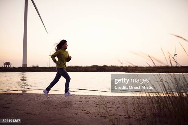 young woman jogging by the river. - riverbank stockfoto's en -beelden