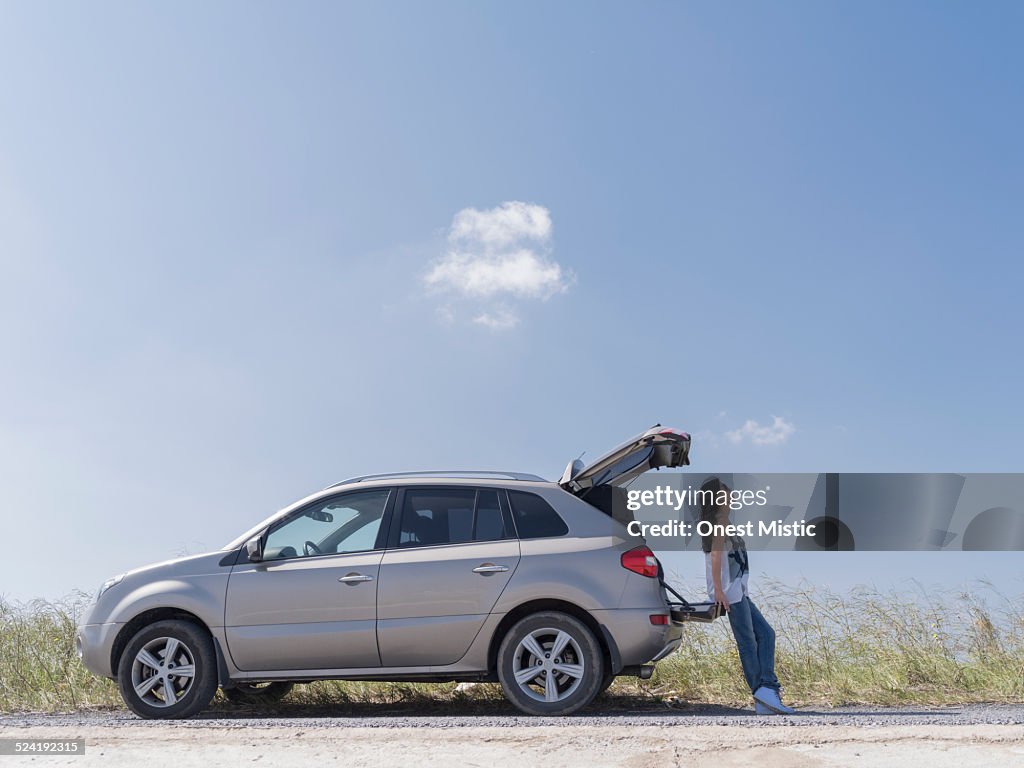 Woman leaning on trunk of car