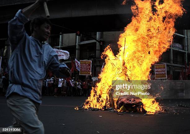 Protester dances around a burning effigy depicting President Aquino during a demonstration outside the presidential palace in Manila, Philippines,...