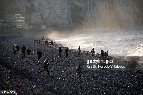 People at the beach are silhouetted against the cliffs in Dieppe, France, 28 December 2014, while enjoying the afternoon sun at the sea side. The sun...