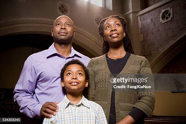 famiglia in piedi e pregare in chiesa - pregare fede foto e immagini stock