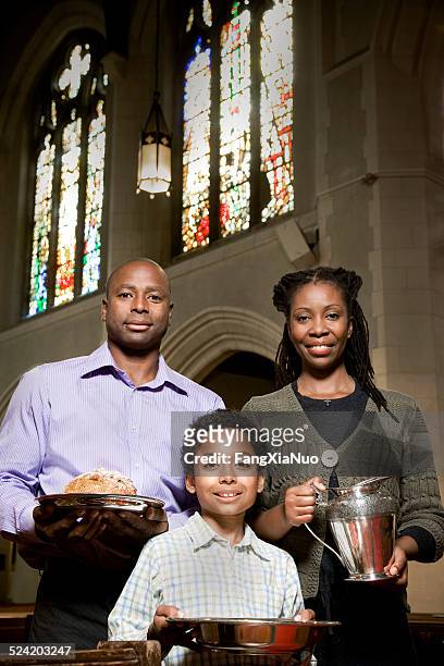 young family in church aisle with bread and wine - black people praying stock pictures, royalty-free photos & images