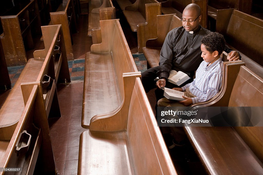 Prete e ragazzo in chiesa Pew lettura Bibbia