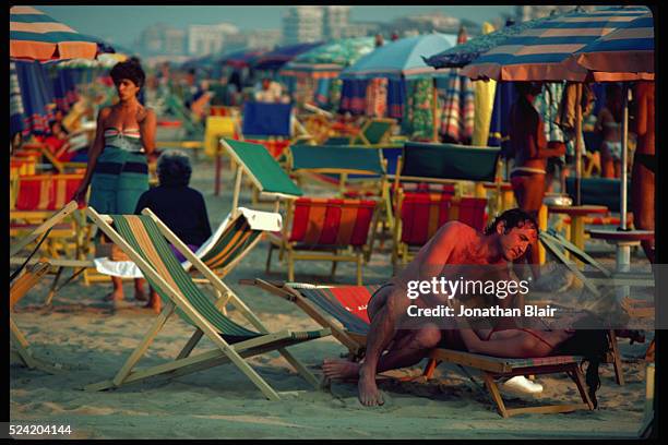 Couple embraces on a lounge chair on the beach in Rimini, Italy.