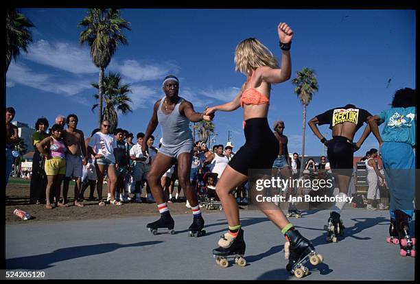 Roller skaters dance on the walkway at Venice Beach, California.