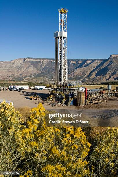 Rig drills for natural gas, framed by the cliffs of the Roan Plateau and a hill blooming with Rabbit Brush. New wells will add to some 7,500...