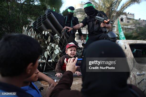 Palestinian woman takes picture to her son on a military truck during a parade for militants of the Ezzedine al-Qassam brigade, the armed wing Hamas...