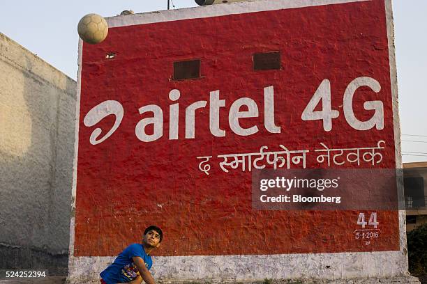 Boy throws a ball in front of a painted advertisement for Bharti Airtel Ltd. Displayed on the side of a building in Murthal, Haryana, India, on...