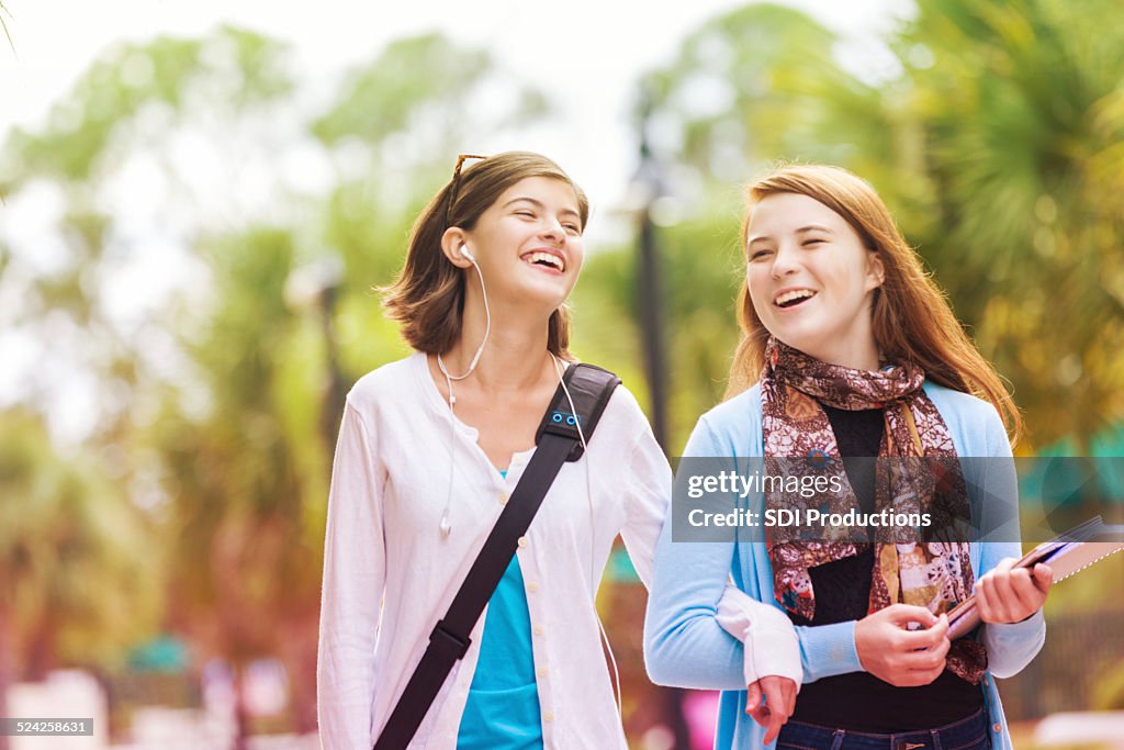 Cute adolescent girls walking to bus stop before school