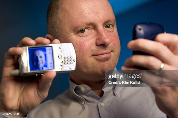 Sean Maloney, Executive Vice President and General Manager, Intel Communications Group poses with his Treo cell phone with keyboard and camera, left...