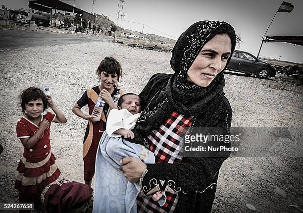 Mother holds her nine-day-old bay named Aara from the sun as she waits with her family at a checkpoint in Badriya where temperatures reached 45C. The...