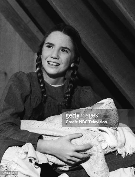 American actress Melissa Gilbert holds a baby doll in a scene from the episode 'Be My Friend' of the television series 'Little House on the Prairie,'...