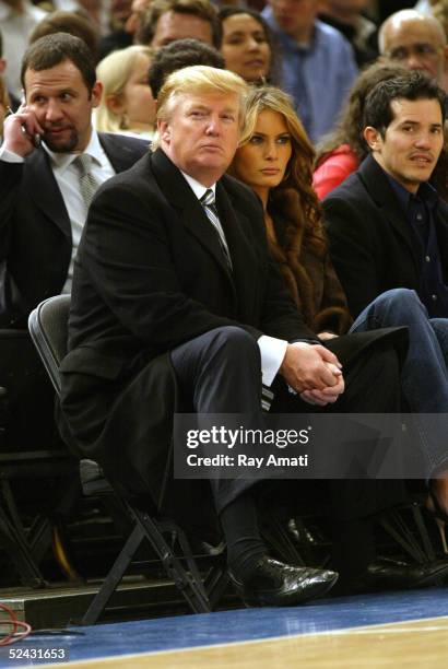 Donald Trump, his wife Melania Trump, and actor John Leguizamo sit courtside during the Miami Heat and New York Knicks NBA game on March 15, 2005 at...