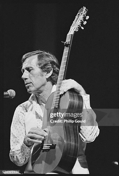 Country musician Chet Atkins holds his acoustic guitar vertical while performing on stage.