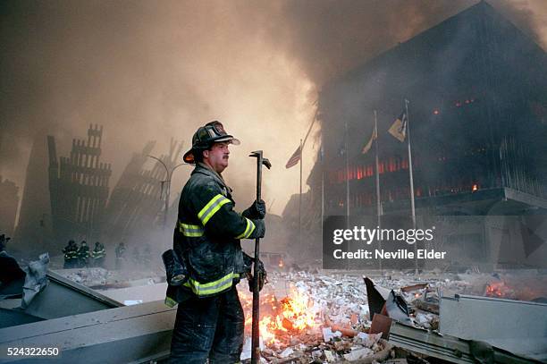 New York City firefighter stands among the rubble near a burning building at Ground Zero at the site of the Twin Towers at the World Trade Center....