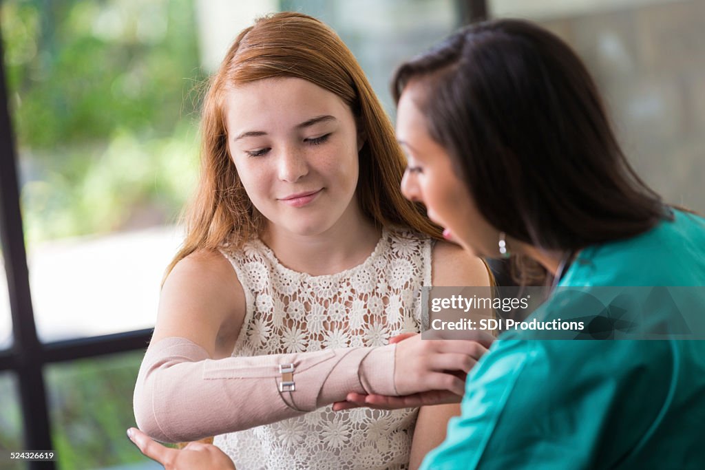Nurse examining teen patient's broken or injured arm