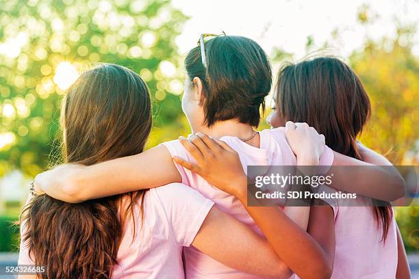 women embracing after finishing breast cancer awareness race - vrouwenkwesties stockfoto's en -beelden