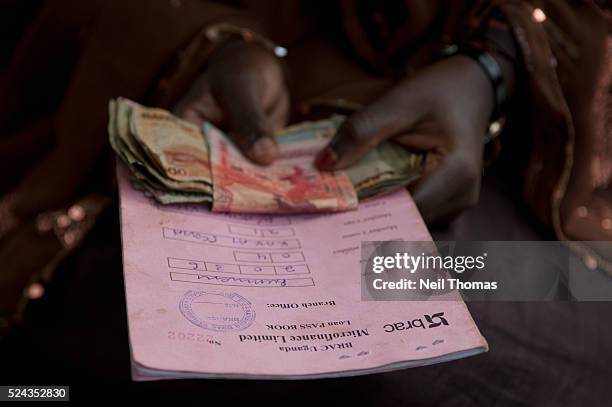 Woman repays her loan at a community microfinance meeting in Uganda. Microfinance has become an important tool in developing countries by providing...